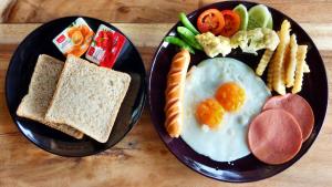 Ban Khun Yuam昆元度假酒店的两盘黑盘早餐食品,包括鸡蛋和烤面包