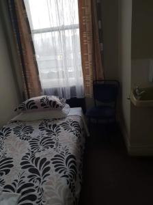 泰哈皮Gretna Hotel Taihape的一间卧室配有一张带枕头和窗户的床