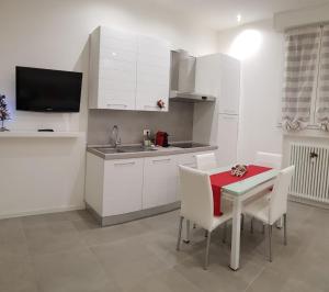 博洛尼亚Sweet Home Sofia的厨房配有白色橱柜和红色的桌椅