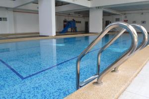 新山阿曼萨丽公寓度假酒店的一个带蓝色水和银栏杆的游泳池