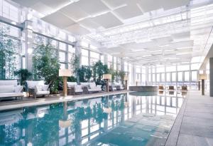 釜山釜山柏悦酒店的一座带白色家具和窗户的建筑中的游泳池