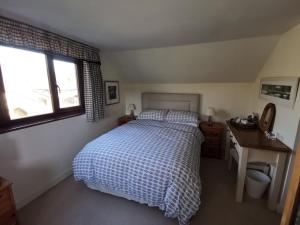 艾维布里奇Thornham Cottage的一间卧室配有一张床、一张书桌和一个窗户。