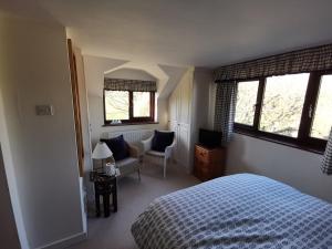 艾维布里奇Thornham Cottage的一间卧室配有一张床、一把椅子和窗户。
