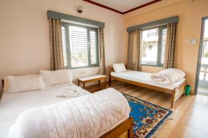 博卡拉Hotel Mountain View - Lakeside Pokhara的一间卧室设有两张床和两个窗户。