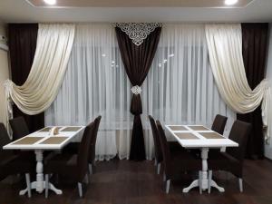 RomnyОрхідея的用餐室配有2张桌子和椅子以及窗帘
