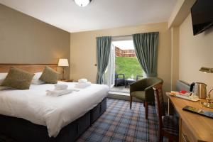 锡豪西斯The Bamburgh Castle Inn - The Inn Collection Group的配有一张床、一张书桌和一扇窗户的酒店客房