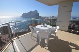 卡尔佩Apartamentos Entremares - Grupo Antonio Perles的阳台上配有白色的桌椅,享有海景
