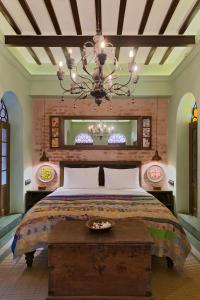 加尔各答Calcutta Bungalow的一间卧室配有一张大床和一个吊灯。