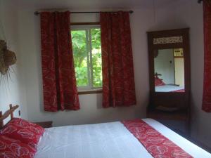 维拉港贝尔维尤生态山林小屋的一间卧室配有一张带红色窗帘和镜子的床