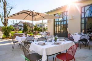 卡斯泰勒雅卢Hotel Clos Castel的一间设有白色桌椅和遮阳伞的餐厅