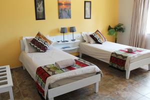 奥马鲁鲁Omaruru Guesthouse的黄色墙壁客房的两张床