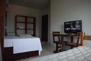 伊塔佩马Pousada Vovo Valdir的客房设有一张床和一张桌子及一台电视