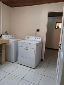 阿拉胡埃拉Kubo Apartment的洗衣房,配有2台洗衣机,并有门通往另一间客房