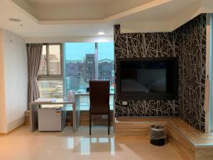 中坜以琳商务旅馆的客厅配有电视和带椅子的桌子