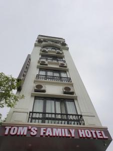 下龙湾Tom's Family Hotel的一座高大的白色建筑,上面有家庭酒店标志