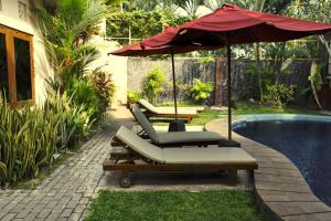 塞米亚克尼拉玛雅别墅酒店的一组躺椅和一把遮阳伞,位于游泳池旁