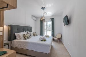 克洛瓦斯米科诺斯岛弗洛拉公寓的一间卧室配有一张带白色床单的床和一扇窗户。