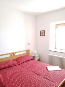 圣博沃"La Casina" Relax e Natura a Canal San Bovo的一间卧室配有一张带红色床单的床和一扇窗户。