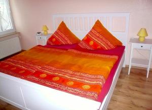 ZirchowFerienwohnung Fam. Gansau - Insel Usedom的一张带红色和橙色毯子及枕头的床