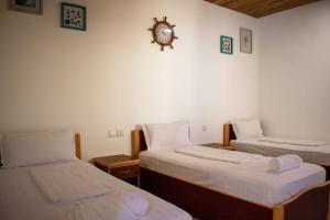 亚喀巴达纳潜水员村庄旅馆的一间设有两张床的客房和墙上的时钟