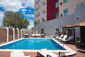 阿瓜斯卡连特斯Hyatt Place Aguascalientes Bonaterra的一座带椅子的酒店游泳池以及一座建筑