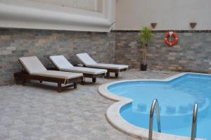 赫尔格达Elite Suites Hurghada的一个带躺椅的游泳池和一个游泳池