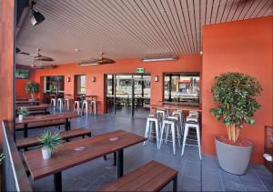 悉尼Kingsgrove Hotel的餐厅设有木桌和椅子,拥有橙色的墙壁