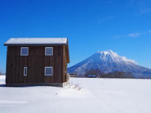二世古Niseko Highland Cottages的雪中的房子,背景是山
