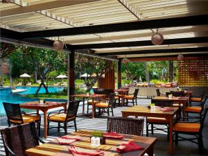 芒希Mangsit Suites by Holiday Resort Lombok的一间带桌椅的餐厅和一个游泳池