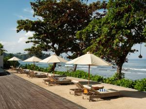芒希Mangsit Suites by Holiday Resort Lombok的海滩上的一组椅子和遮阳伞