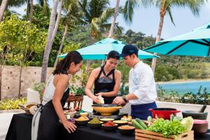 塔林甘海滩Avani Plus Samui Resort的一群人站在桌子旁吃着食物