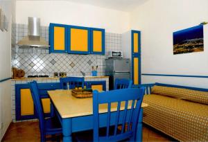 法维尼亚纳Residence Punta Longa的厨房配有蓝色和黄色的橱柜以及桌椅