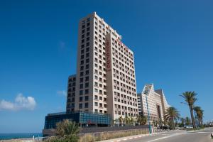 海法master Haifa Beach Apartments的一座高大的白色建筑,上面有时钟