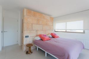 塞斯科维特Maison Ses Covetes的卧室配有粉红色的床和砖墙
