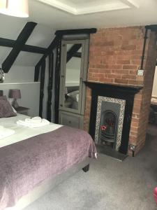 威尔汉姆Anglebury House的一间卧室配有一张床和一个砖砌壁炉