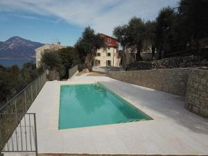 托里德尔贝纳科Agriturismo Le Anze的一座石头墙旁边的游泳池和一座房子