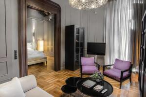 塞维利亚CoolRooms Palacio Villapanés的客厅配有紫色椅子和1张床