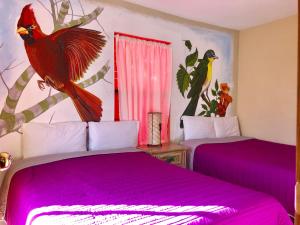 Mesa ColoradaHotel JADE的一间卧室配有两张紫色床单和一只鸟放在墙上的卧室