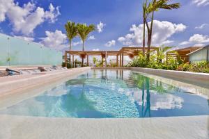 普拉亚卡门纽波特豪斯海滩精品酒店的一座拥有蓝色海水和棕榈树的游泳池