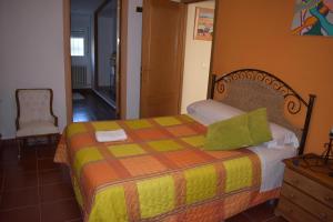 波索阿尔孔Alojamientos Rurales la Loma的一间卧室配有一张黄色和橙色毯子的床