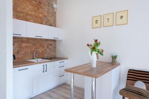 波兹南PROVENIR HOME STRZELECKA 25的厨房配有白色橱柜和木桌