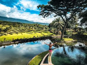 外南梦Ijen Resort and Villas - The Hidden Paradise的站在公园池塘前的小路上的女人