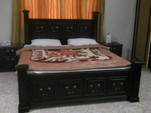 木尔坦Sunrise Guest House Multan的一间卧室配有一张木架床