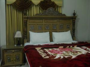 木尔坦Sunrise Guest House Multan的一间卧室配有一张大床和木制床头板