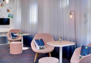 维希Hôtel ibis Styles Vichy Centre的一间设有两张桌子和椅子、一张桌子和两张桌子及椅子的房间
