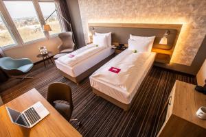 勒沃库森Leoso Hotel Leverkusen的酒店客房配有两张床和一张书桌
