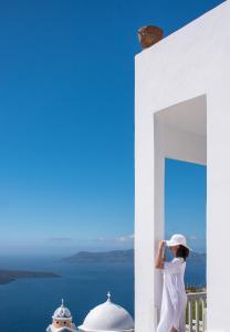 费拉Amelot Art Suites的站在一个眺望海洋的阳台上的女人