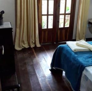 穆库热Jardim das orquídeas的一间卧室配有一张带蓝色毯子的床和两个窗户。