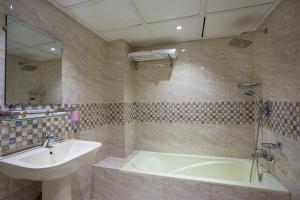 达卡HOTEL THE CAPITAL LTD.的一间带水槽、浴缸和镜子的浴室