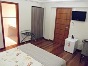 圣安娜-利弗拉门图Hotel Acrópolis的配有床、电视和椅子的房间